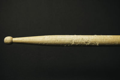 Close-up of wooden drumstick against black background