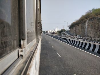 Road seen through bus window against clear sky