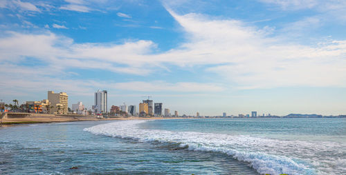 Scenic view of sea by buildings against sky