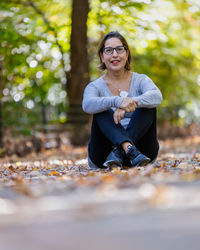 Portrait of young woman sitting on footpath