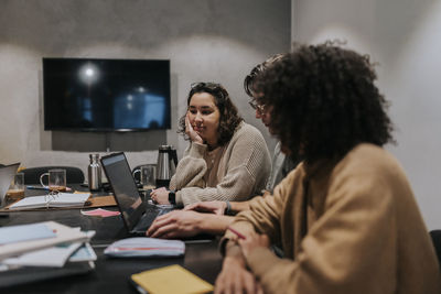 Multiracial computer programmers discussing over laptop in board room at office