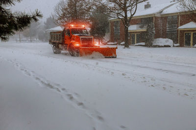 Snow covered street by buildings in city during winter