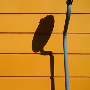 Close-up of shadow of satellite dish on orange wall