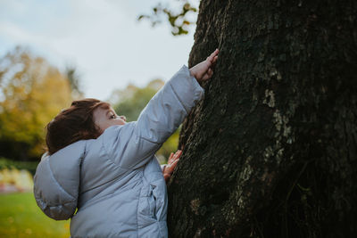 Cute baby girl touching tree in park