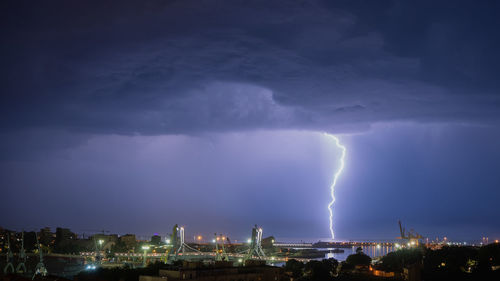 High angle view of illuminated cityscape against sky at night inc lightning strike