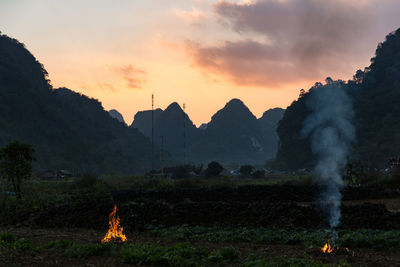 Panoramic view of bonfire on field against sky during sunset