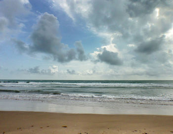 Scenic view of beach against cloudy sky