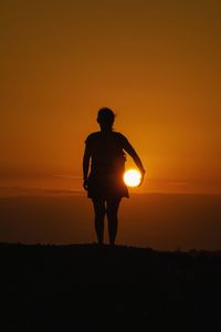 Optical illusion of woman holding sun during sunset