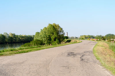 Road amidst trees against clear sky