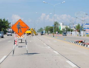 Construction sign on road against sky