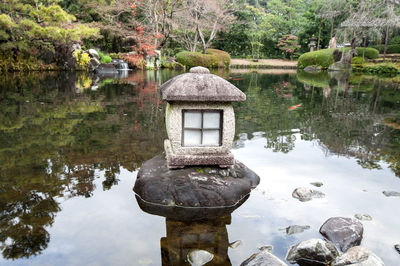 Gazebo on rock by lake in garden