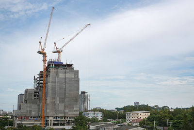 Cranes at construction site against sky in city