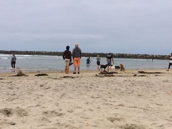 People walking on beach against sky