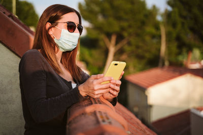 Woman using smart phone while standing in balcony