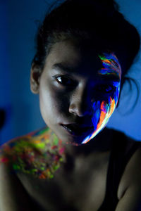 Close-up portrait of young woman with paint on face and shoulder