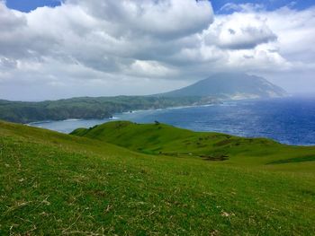 Scenic view of landscape by sea against sky