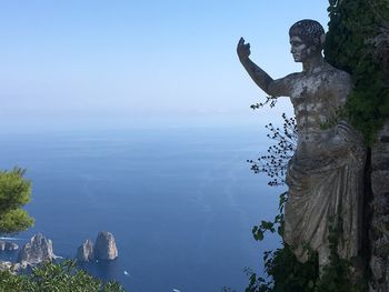 Statue by sea against clear sky
