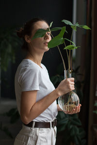 Young woman with arms raised standing against plants