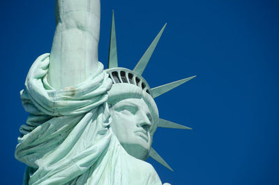 Low angle view of statue of liberty against blue sky