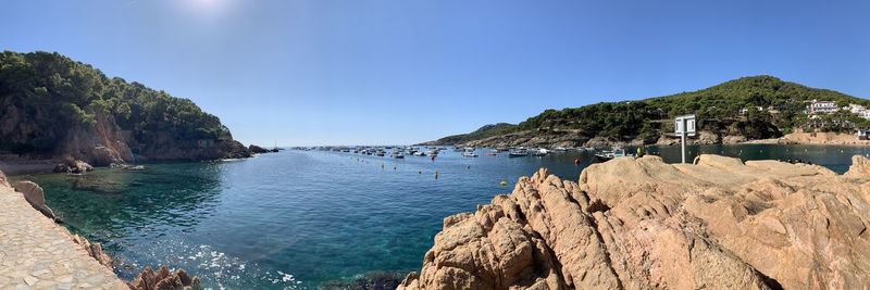 Panoramic view of sea and rocks against clear blue sky