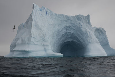 Scenic view of ice cave in sea against sky during winter