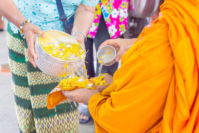 Midsection of woman holding yellow flower