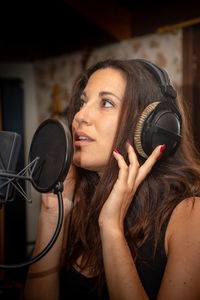 Beautiful woman singing in microphone at studio