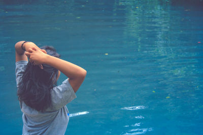 Rear view of woman standing by swimming pool