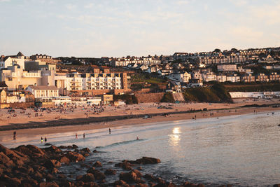 Aerial view of buildings by sea against sky