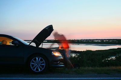 Man in car against sky during sunset