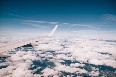 Airplane flying over cloudscape against blue sky