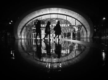 People walking in illuminated water at night