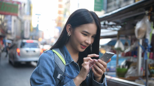 Young woman using mobile phone in city