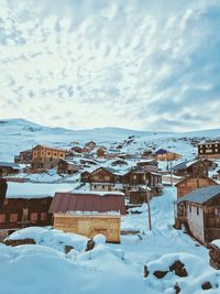 Houses on snow covered mountain against sky