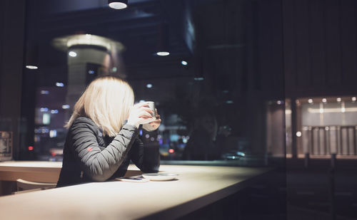 Woman sitting in cafe seen through glass