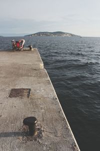 People on pier by sea against sky