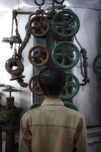 Rear view of man standing on old machine