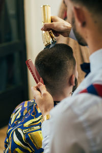 A barber cuts the hair of a customer with a clipper