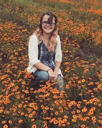 Portrait of smiling young woman sitting on autumn leaves