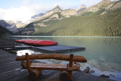 Wooden table by lake against mountains
