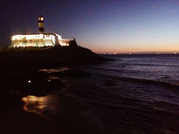 View of illuminated building at beach during sunset
