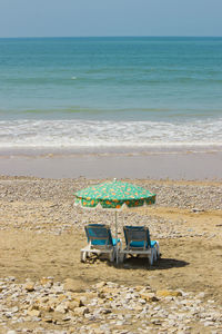 Photo of beach chairs and an umbrella on the ocean