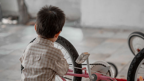 Rear view of man standing on bicycle
