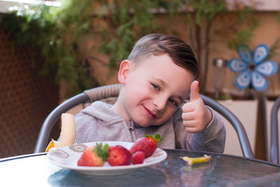 Portrait of young woman eating food on table