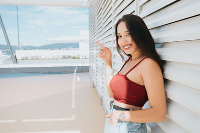 Portrait of young woman standing against sky