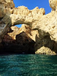 Rock formation by sea against sky