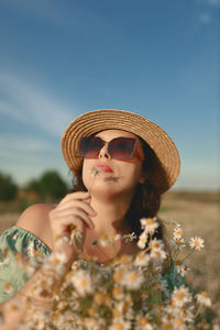 Portrait of young woman wearing hat against sky