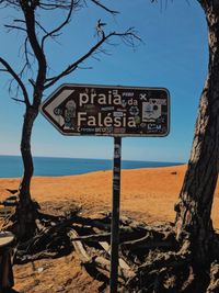 Information sign on tree trunk against blue sky