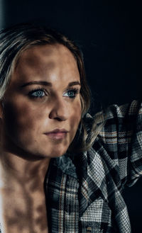 Close-up portrait of young woman against black background