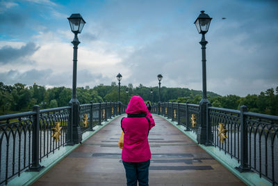 A woman with pink jacket standing in front of tsaritsyno park bridge